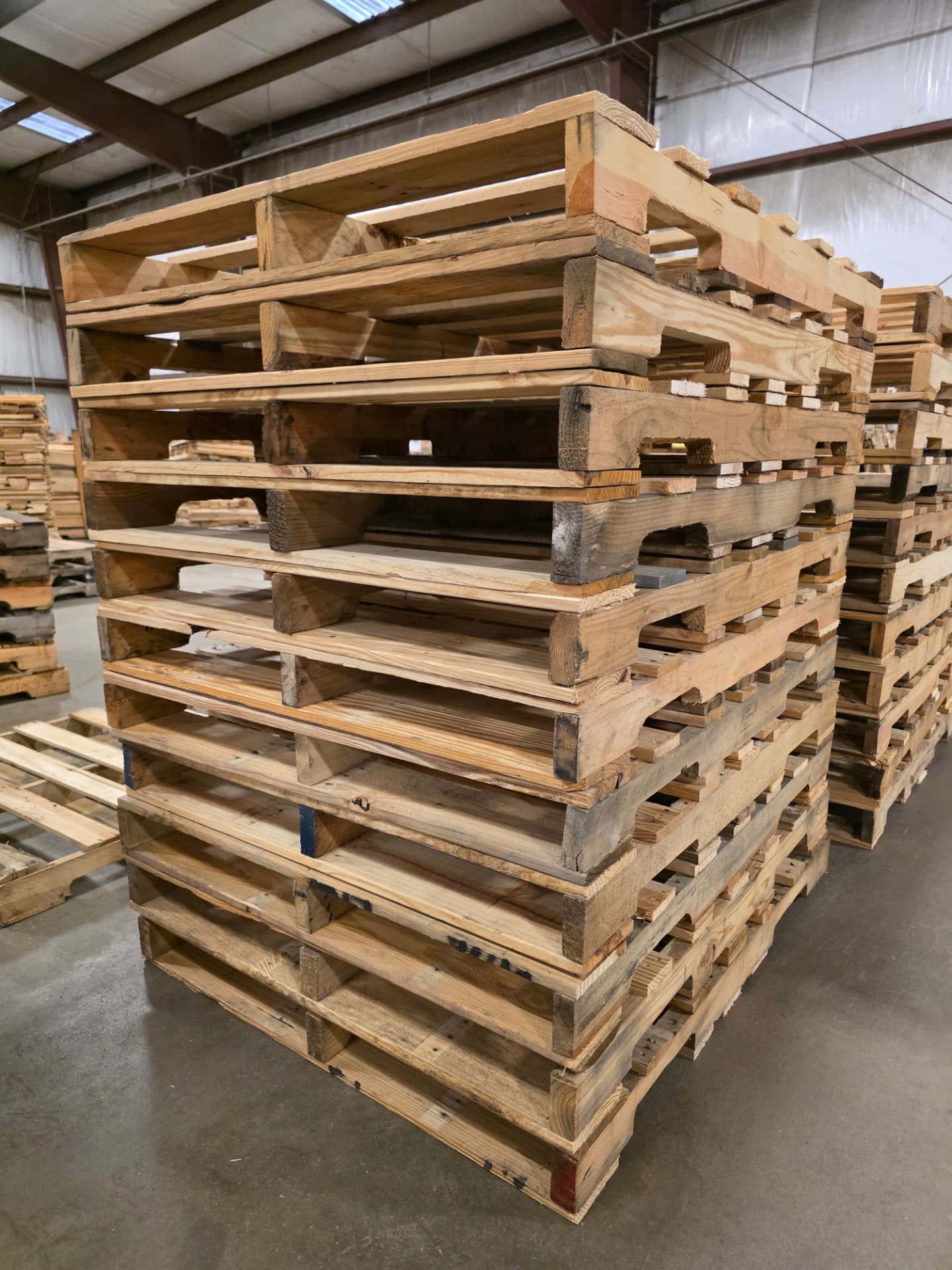 Recycled wooden pallets stacked inside the Quality Pallet Systems warehouse